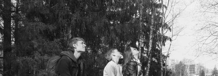 Children of different ages and genders sit on a park bench and look at the skyの写真素材