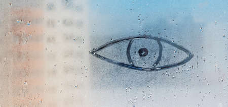 A painted eye on the misted spring glass of a plastic windowの写真素材