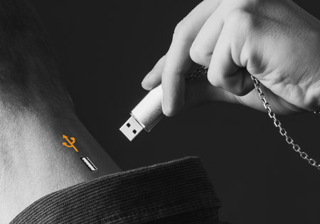 Collage, a man's hand holding a flash drive on a chain inserts it into another person's headの写真素材