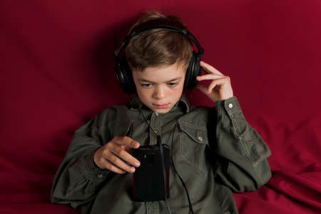 Tinted image of a little boy listening to music with headphones on his phoneの写真素材