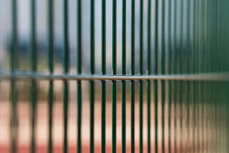 Fragment of a metal fence of a sports ground of dark green colorの写真素材