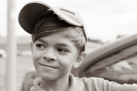 Black and white photo.A small boy in a t-shirt and cap poses for the camera