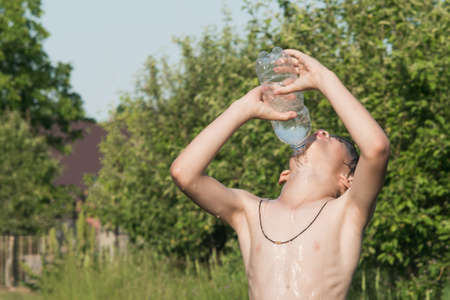 A little boy douses himself with water in hot weather outside the cityの写真素材