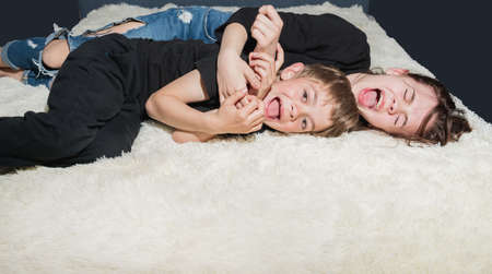 Brother and sister play on the bed with a new white terry capeの写真素材