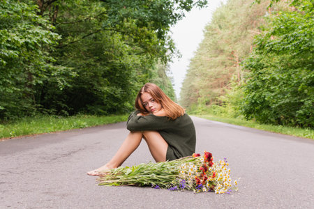 Portrait image of a young girl with a bouquet of wild flowers on a forest road