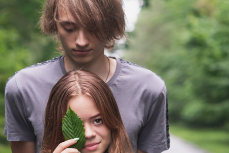 A young girl and a guy are walking along a forest road outside the cityの写真素材