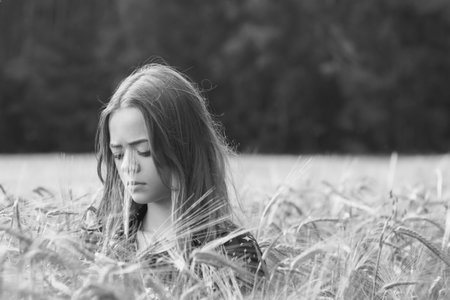 Portrait image of a young girl walking in a field sown with wheat