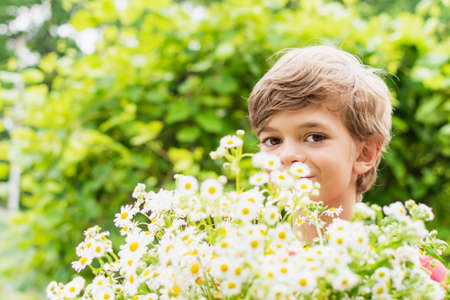 A little boy with a large bouquet of flowers in the summer gardenの写真素材