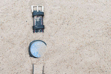 A wristwatch with a leather bracelet lies lost in the sand on the beachの写真素材
