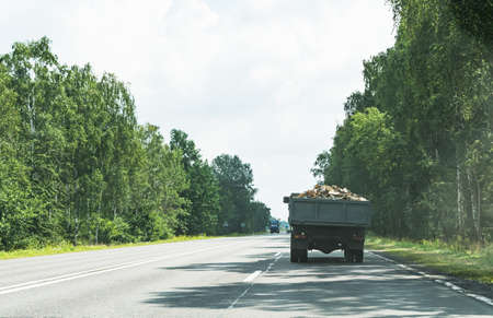 An old cargo flatbed car carries firewood on the roadの写真素材