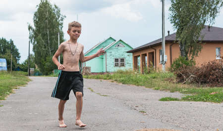 A little boy walks around the village barefoot and without a T-shirtの写真素材