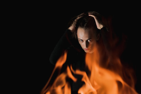 The view of an adult guy with long hair through the fire in complete darknessの写真素材