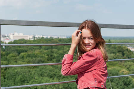A young girl looks at the city from a panoramic balcony on the observation deckの写真素材