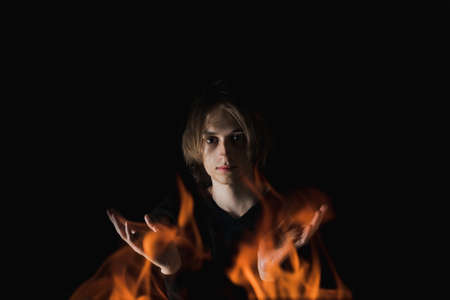 The view of an adult guy with long hair through the fire in complete darknessの写真素材