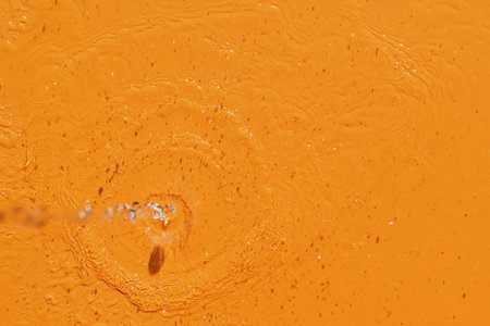 View of the pouring water with splashes on an orange backgroundの写真素材