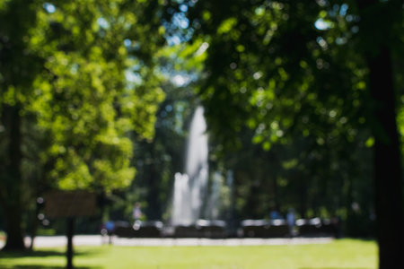 A blurry image of a people's recreation park with a fountain and an embankmentの写真素材