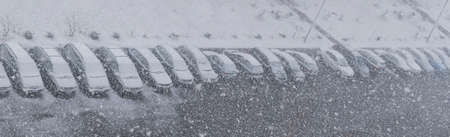 A blurry image of a parking lot with cars during a snow storm in winterの写真素材