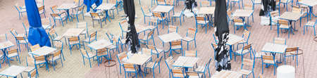 Empty tables and chairs of the summer cafe are placed on a large territoryの写真素材