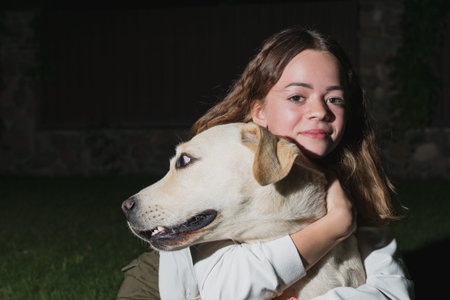 A young girl plays with a light labrador dog in the evening