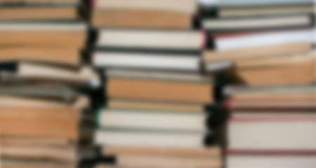 A blurry image of old books stacked in pilesの写真素材