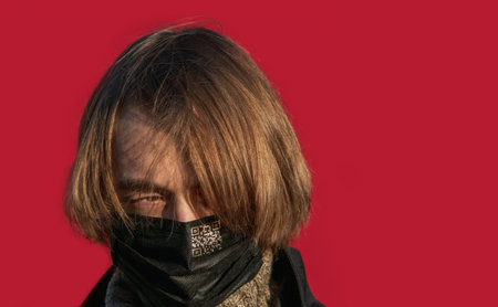 A young guy with long hair in a protective medical mask