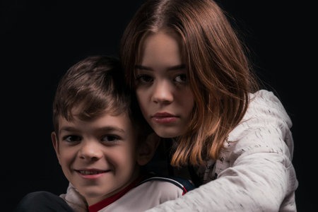 A girl plays with her younger brother on a dark backgroundの写真素材