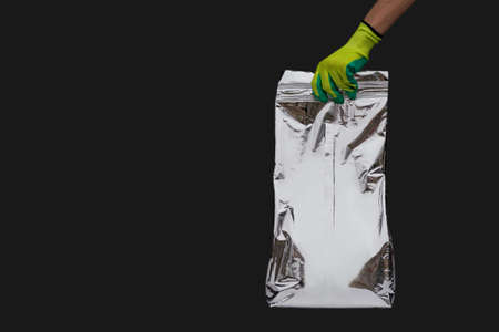 A worker wearing gloves holds a shiny grocery bagの写真素材