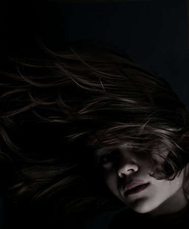 Portrait of a young girl with makeup and long hair in the darkの写真素材