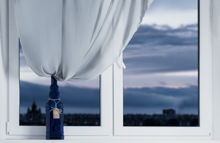 Decorative bottle on the windowsill with a curtain