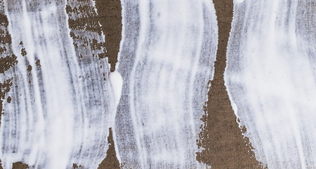 Brush stroke of white paint on rough material