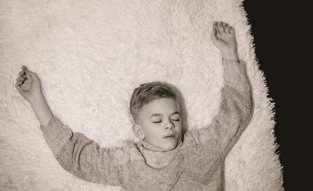 A little boy sleeps on a sofa with a velvet cape