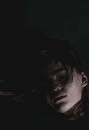 Portrait image of a young girl in a dark roomの写真素材