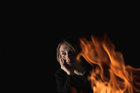 The view of an adult guy with long hair through the fire in complete darkness
