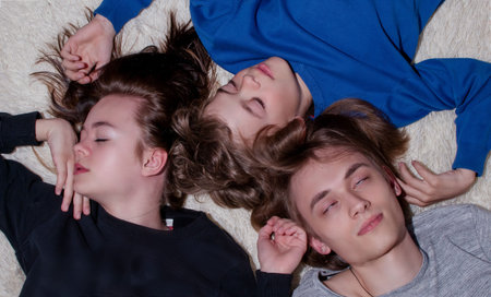Brothers and sister are lying on the couch