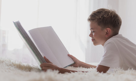 A little boy looks at a photo album on the bed in the roomの写真素材
