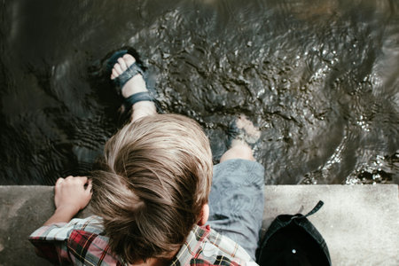 A little boy walks in the park, wetting his feet in water