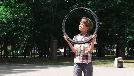 A little boy walks in the park, carries a tire from a bicycleの写真素材