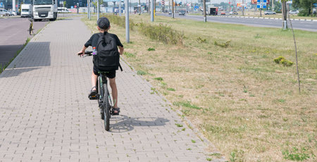 A little boy rides around the city on a bicycle with a backpack