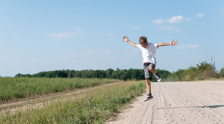 A little boy in a white T-shirt runs merrily along a country road