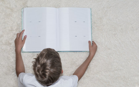 A little boy looks at a photo album on the bed in the room