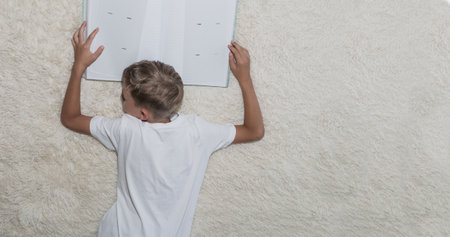 A little boy looks at a photo album on the bed in the roomの写真素材