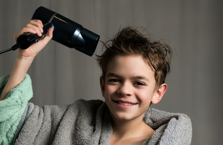Portrait of a boy drying his hair with a hairdryerの写真素材