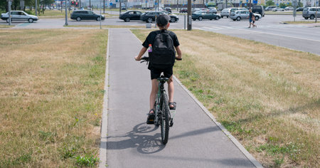 A little boy rides around the city on a bicycle with a backpackの写真素材
