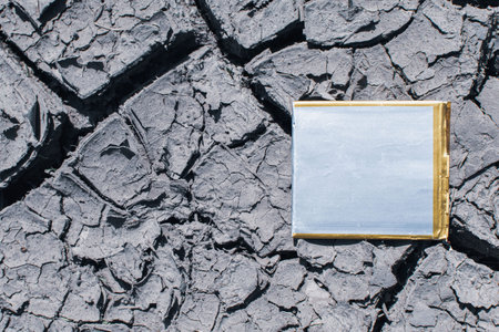 An old small lithium-ion battery is lying on the cracked ground