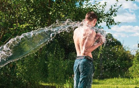 A young guy is doused with waterの写真素材