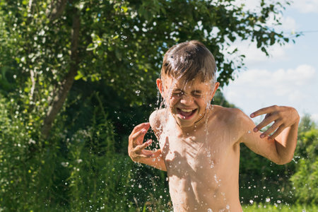 A little boy is doused with water on a country plotの写真素材