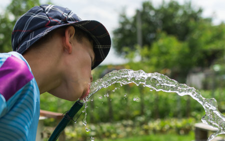 Image of a little boy on the background of a water fountain on a country plotの写真素材