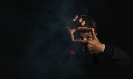 A little boy is sitting by a smoking fire in the darkの写真素材