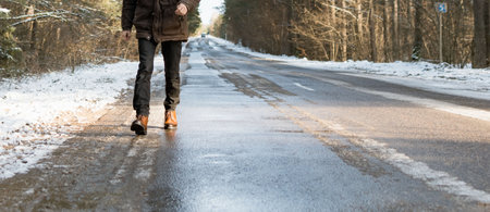 A man in new boots walks along a snowy road outside the cityの写真素材
