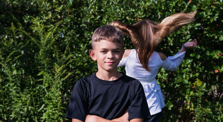 Portrait image of a little boy with his older sister in a summer garden